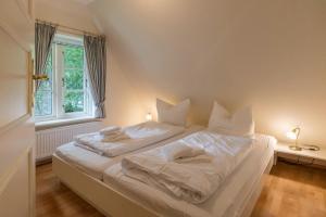 ein weißes Bett in einem Zimmer mit Fenster in der Unterkunft Ferienwohnung Osterhus in Nieblum