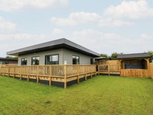 a modular home with a deck and a fence at Meadowbank Lodge in Brandesburton