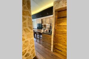 a kitchen with wooden walls and a bar with stools at Le Chappart de Valberg - en plein centre in Péone