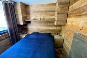 ein kleines Schlafzimmer mit einem blauen Bett und Holzwänden in der Unterkunft Le Chappart de Valberg - en plein centre in Péone