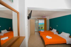 two beds in a room with orange sheets at Elena Studios in Athani