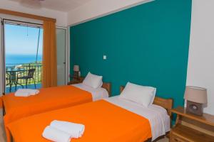 two beds in a room with a view of the ocean at Elena Studios in Athani