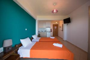 a bedroom with two beds with orange and white sheets at Elena Studios in Athani
