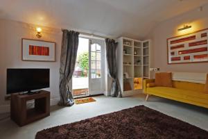 a living room with a yellow couch and a television at Compton House Snug in Newark upon Trent