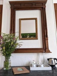 a mirror on a wall with a vase of flowers on a table at La Caminada Vielha in Montaillou