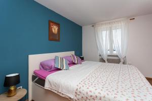 a bedroom with a large bed with purple pillows at Apartments Riva in Baška