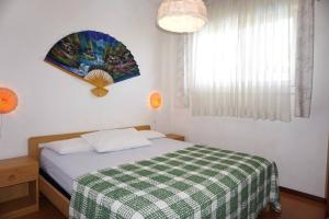 1 dormitorio con 1 cama con manta blanca y verde a cuadros en Spacious villa with private garden and pool, en Porto Santa Margherita
