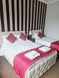 two beds in a hotel room with red and white sheets at Dalry Guesthouse in Edinburgh