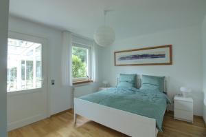 a white bedroom with a bed and a window at Haus Tapken mit Meerblick in Varel
