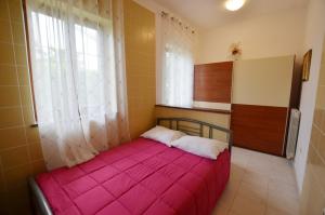 a small bedroom with a pink bed with a window at Zminj Apartments in Žminj