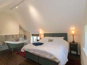 a bedroom with a large bed and a bath tub at Lilac Cottage in Wells