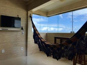 a hammock in a room with a large window at Edf. Maison Chateaubriand in Maceió