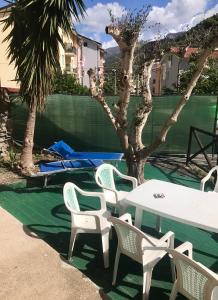 un grupo de sillas blancas, una mesa y un árbol en Le Due Porte, en Maiori