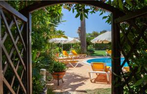 an archway leading into a pool with chairs and umbrellas at L - Wellness Farm in Lagos