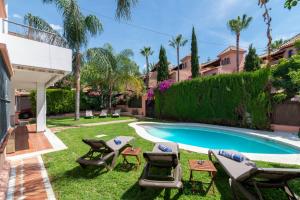 un patio con piscina y sillas y un patio con piscina en Villa Giovanni - Marbella Center - Heated Pool, en Marbella