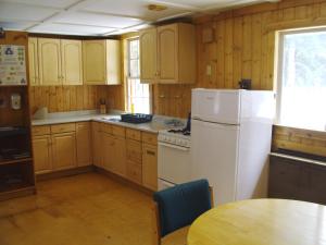 cocina con armarios de madera y nevera blanca en HI Mosquito Creek - Hostel, en Lago Louise