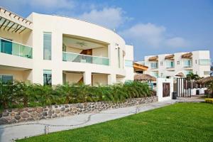 a white building with a stone wall and grass at Artisan Family Hotels and Resort Collection Playa Esmeralda in Chachalacas