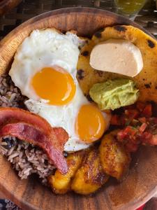a plate of breakfast food with eggs bacon and rice at Kintiri Glamping in Nicoya