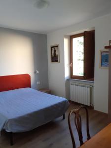 um quarto com uma cama, uma janela e uma cadeira em CIAK Affittacamere em Mulazzo