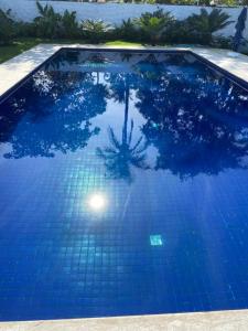 a blue swimming pool with a reflection in the water at Pousada Vila Novo Tempo in Guarujá