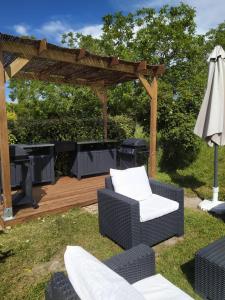 eine hölzerne Pergola mit zwei Stühlen und einem Sonnenschirm in der Unterkunft Les Marmottes Charentaises in Tonnay-Boutonne