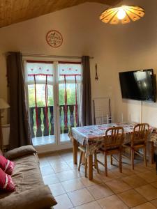 a dining room with a table and chairs and a tv at Appartement dans chalet typiquement savoyard au pied des pistes in La Norma