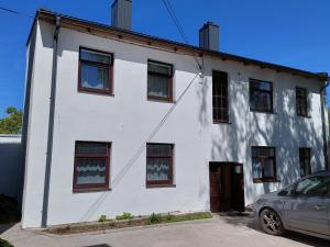 een wit gebouw met ramen en een auto voor de deur bij White box apartment in Liepāja