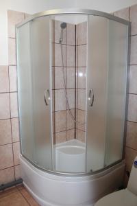 een douche met een glazen deur in een badkamer bij White box apartment in Liepāja +6 foto's