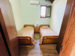 two beds in a small room with a window at Lovely house not far from the beach, near Protaras in Dherinia