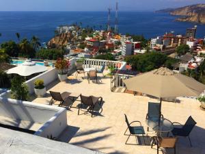 un patio con sillas, mesas y una sombrilla en Penthouse VLM Gran Terraza 200 metros vista inmejorable piscina gigante, en Acapulco