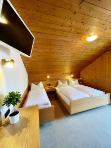 two beds in a room with wooden ceilings at Apartments Spirit of Mountains in Rasun di Sopra