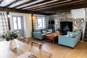 a living room with two blue chairs and a stone fireplace at Inglenook Cottage near Porthcawl and Beaches in North Cornelly
