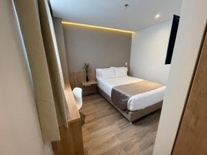 a small bedroom with a bed and a television at ExpoStay Hotel Corferias Embajada Americana in Bogotá