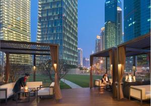 two people sitting at tables on a deck with a city skyline at Mandarin Oriental Pudong, Shanghai in Shanghai