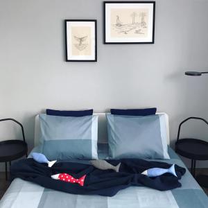 a bed with blue sheets and two pictures on the wall at Morza Szum in Dziwnów