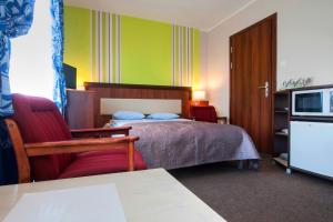 a bedroom with a bed and a chair and a television at Villa Fenix in Ustronie Morskie +78 photos
