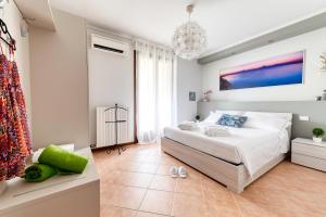 a white bedroom with a bed and a chandelier at Wolf House - Sirmione Holiday in Sirmione