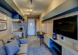 uma sala de estar com um sofá e uma televisão de ecrã plano em Roomo Vila Mariana Residencial Ejoy em São Paulo