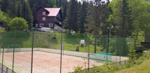 a tennis court in front of a house with a fence at Chata pod Čertovicou in Liptovská Sielnica