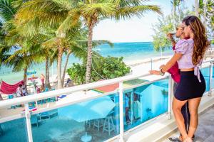 a woman standing on a balcony looking at the beach at Green Coast Beach Hotel in Punta Cana