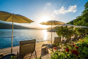 a group of chairs and umbrellas on a dock with a lake at Villa Postillion am See in Millstatt