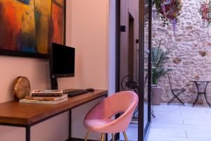 a desk with a chair and a tv at Hôtel Le Milie Rose in Paris