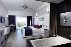 Riu Palace Costa Rica - All Inclusive في كوكو: غرفة في الفندق مع سرير وحوض استحمام