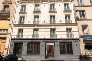 Un grand bâtiment blanc avec des fenêtres donne sur une rue. dans l'établissement Hôtel Le Milie Rose, à Paris