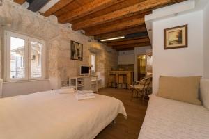 a bedroom with two beds in a room with stone walls at Apartments Stelina in Korčula