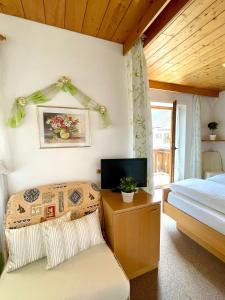 a bedroom with a bed and a tv and a chair at Apartments Spirit of Mountains in Rasun di Sopra