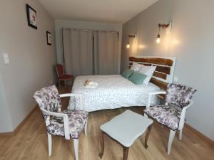 a bedroom with a bed and two chairs at Les Hauts de Grazac in Grazac