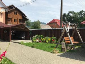 un giardino con altalena in legno di fronte a una casa di Karpatski spohady a Slavske