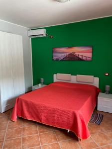 una camera con letto rosso e parete verde di B&b Mula Germaneto a Santa Maria