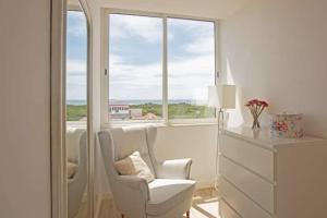 a white room with a chair and a window at Magnificent 1 Bedroom Apartment With Views Over The Ocean in Costa da Caparica